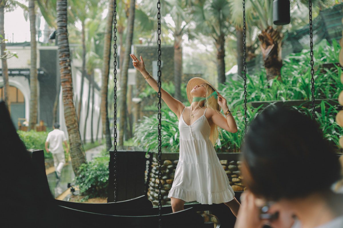 Woman in a white dress on a swing at a tropical resort