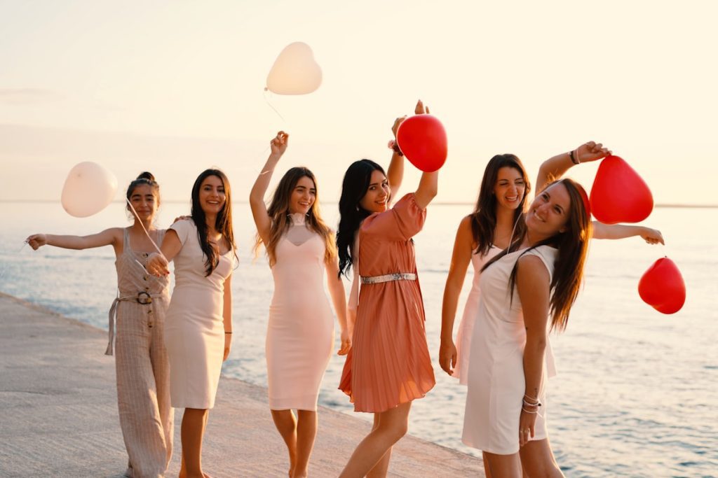 Group of women in elegant resort wear standing near the water