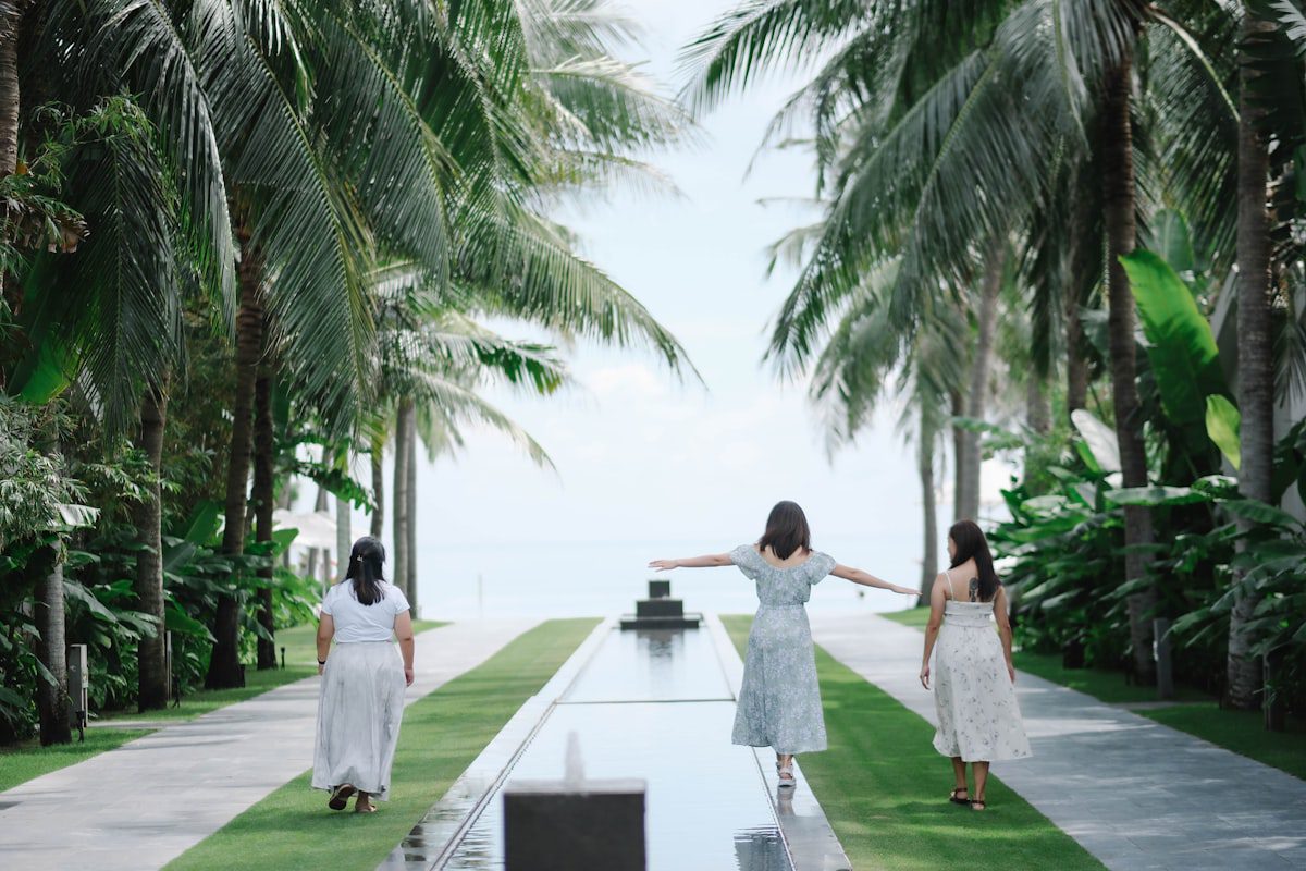 Three women walking down a path towards the ocean