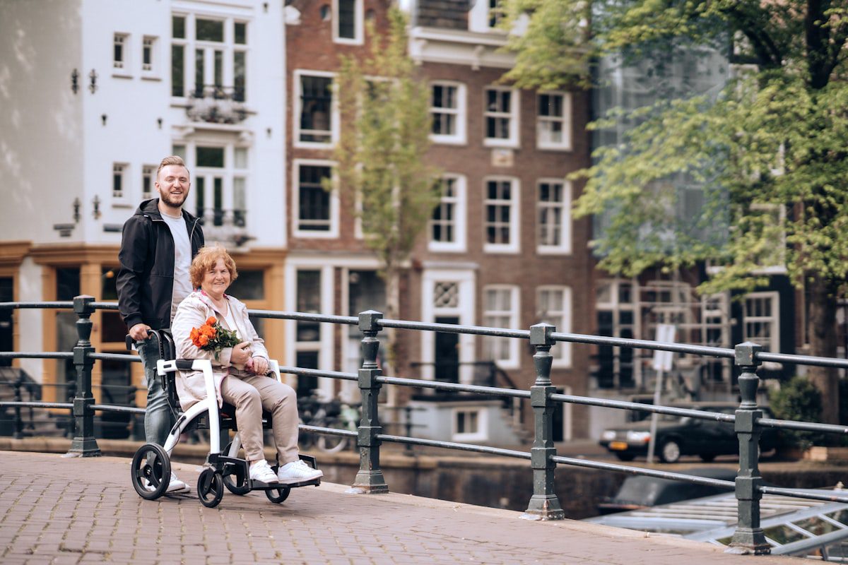 Young man assisting elderly woman in a modern wheelchair outdoors
