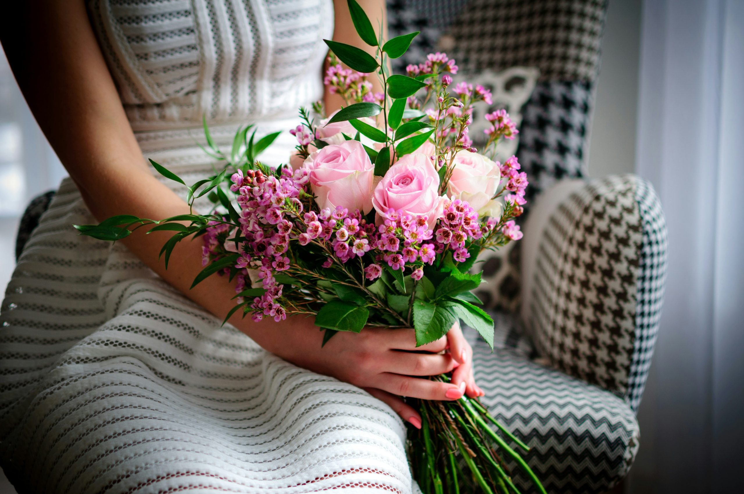 Woman holding a fresh bouquet of pink roses and waxflowers