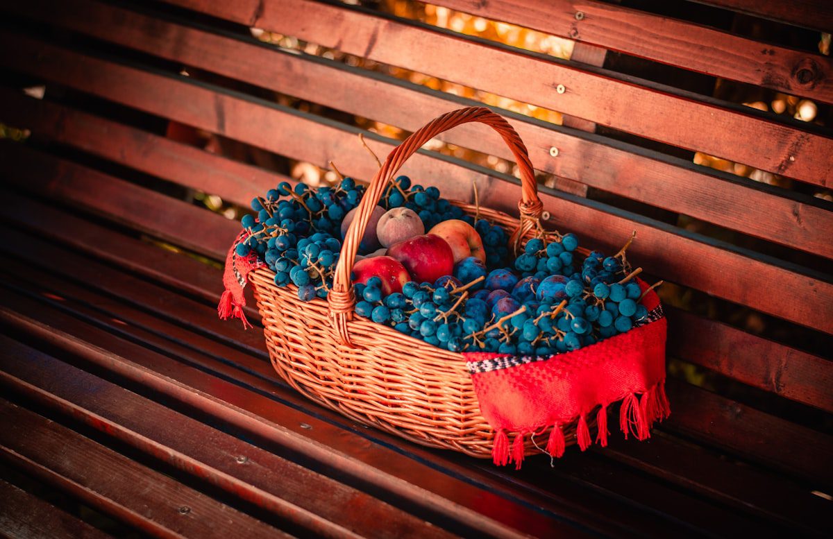 A basket filled with fresh fruit on a wooden bench