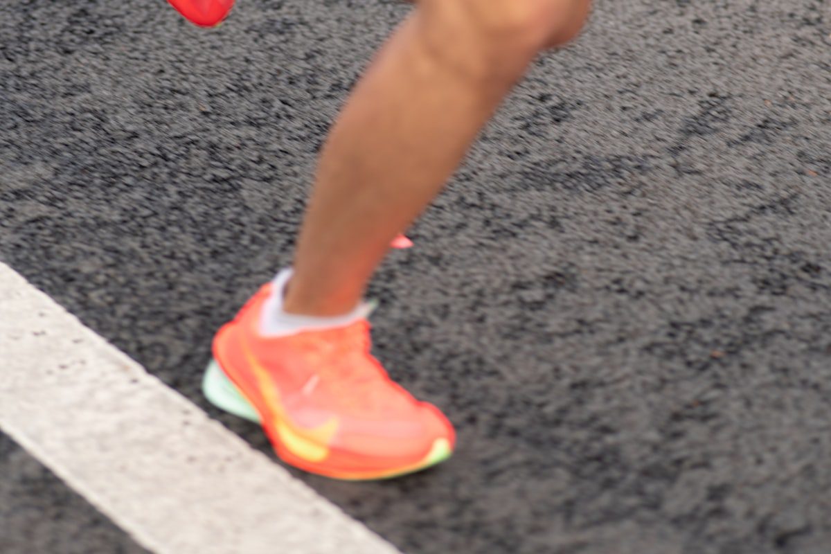 Runner foot in a bright orange athletic shoe on track