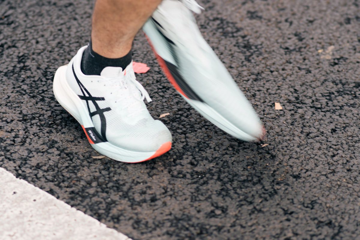 Runner feet in white athletic shoes on pavement