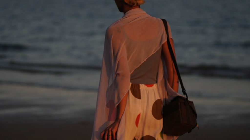 Woman walks alone on the beach at dusk.
