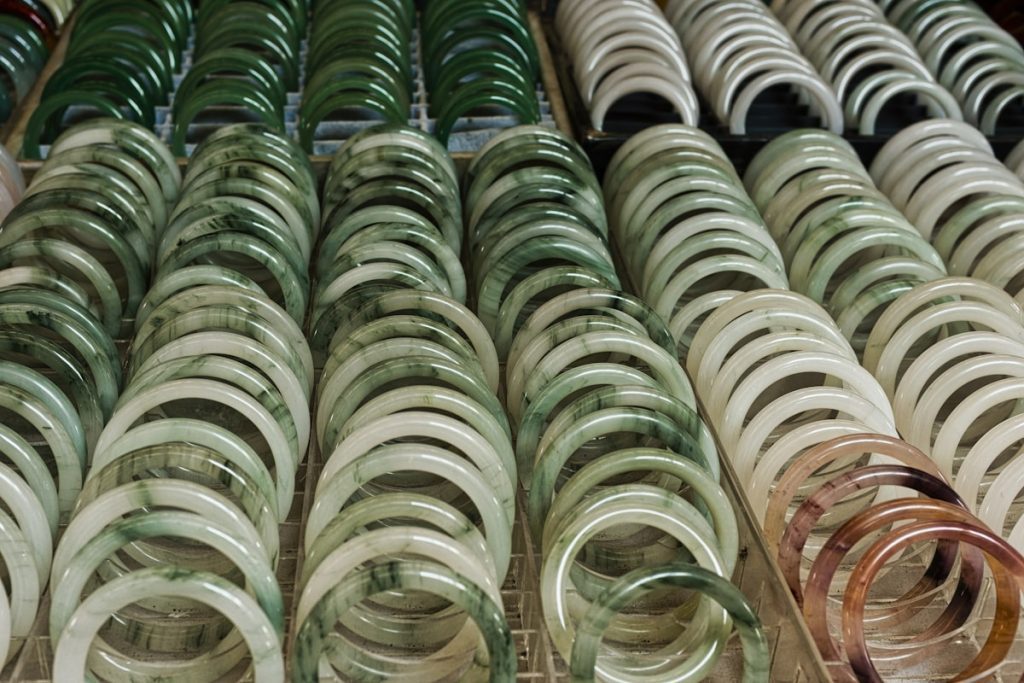 Rows of jade bracelets in various green and white shades at a market