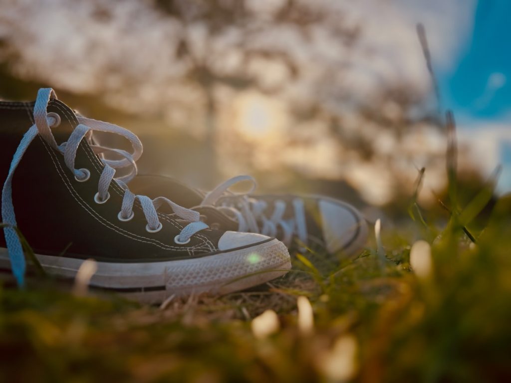 Pair of sneakers resting in grass at sunset